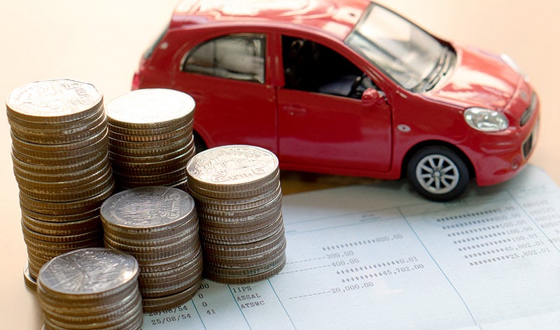 red toy car and stack of coins placed on paper